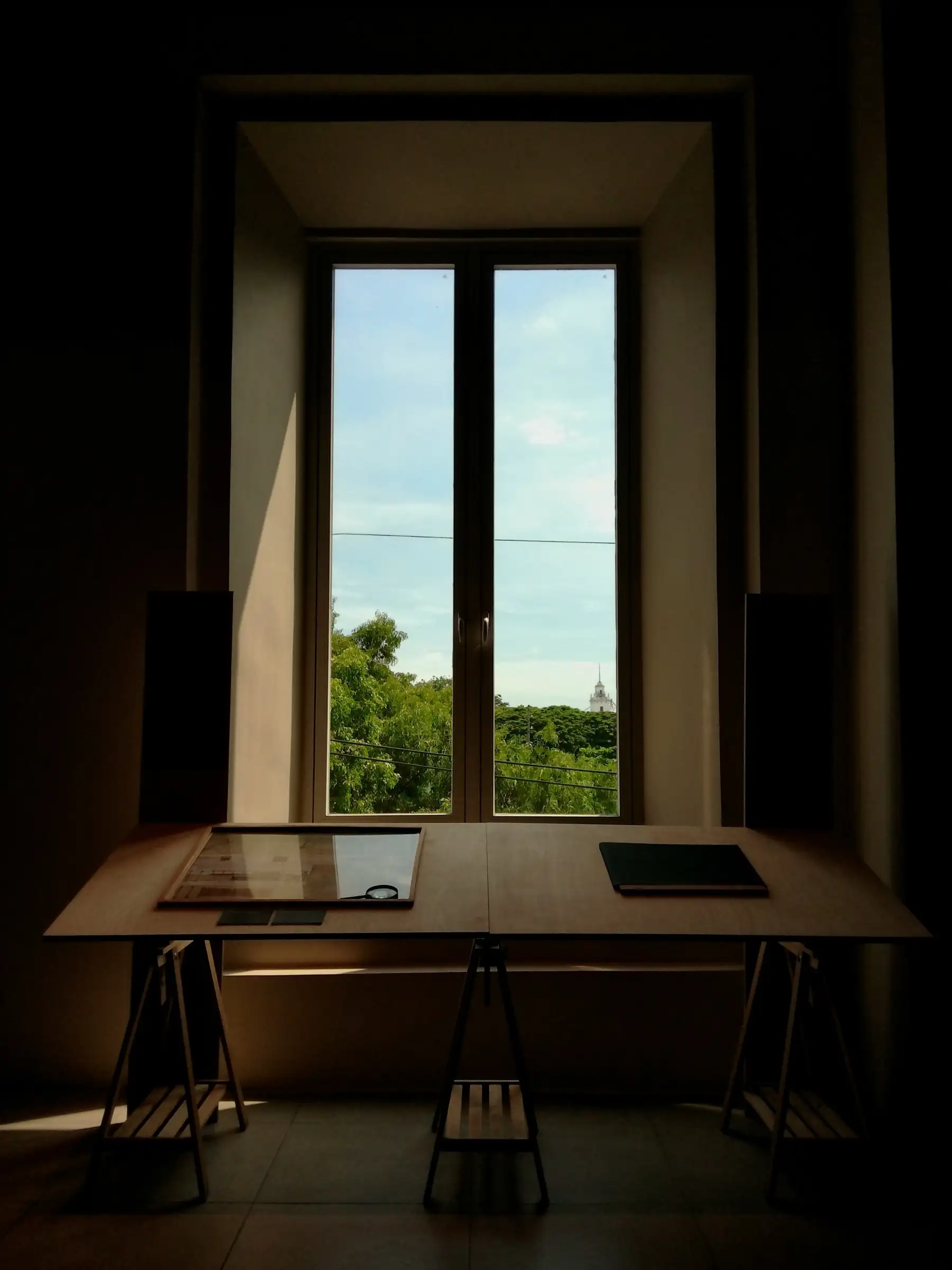 Dark studio with a drafting table in front of a tall window