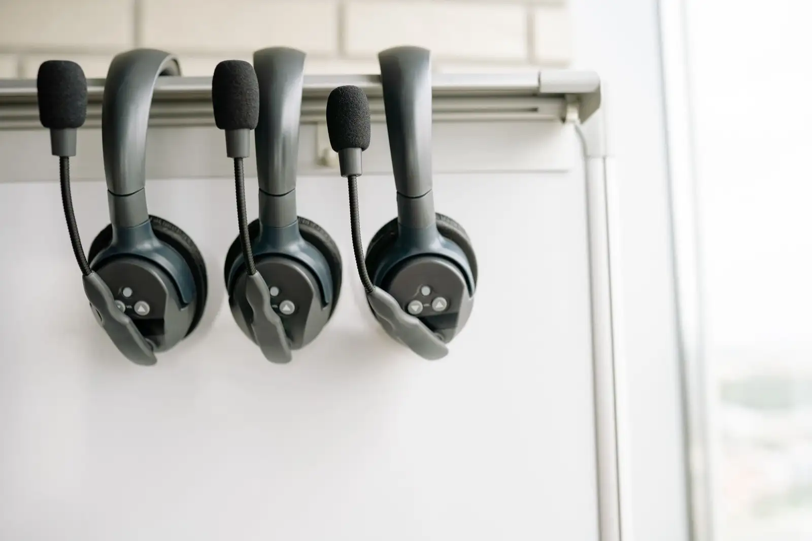 Drei Headsets mit Mikrofon an einer Schiene