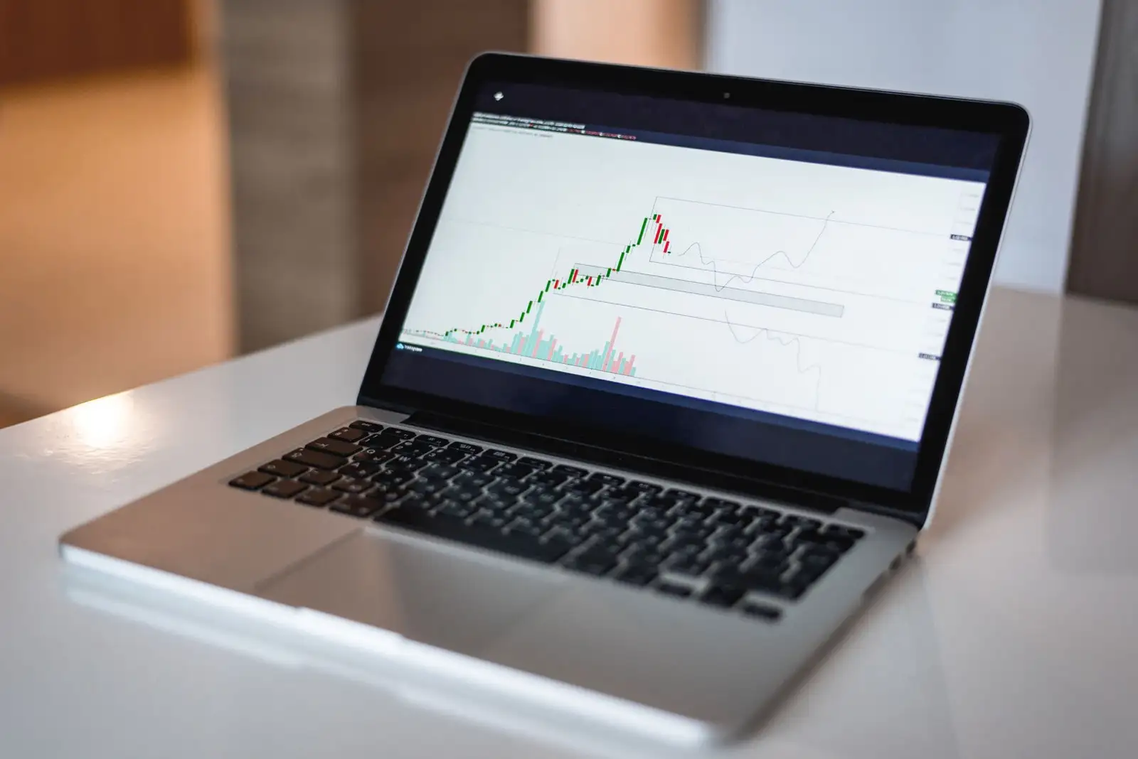 Laptop auf einem weissen Tisch mit einem Finanzdiagramm